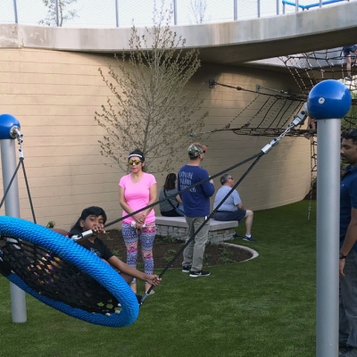 Parents push children on a saucer-style swing